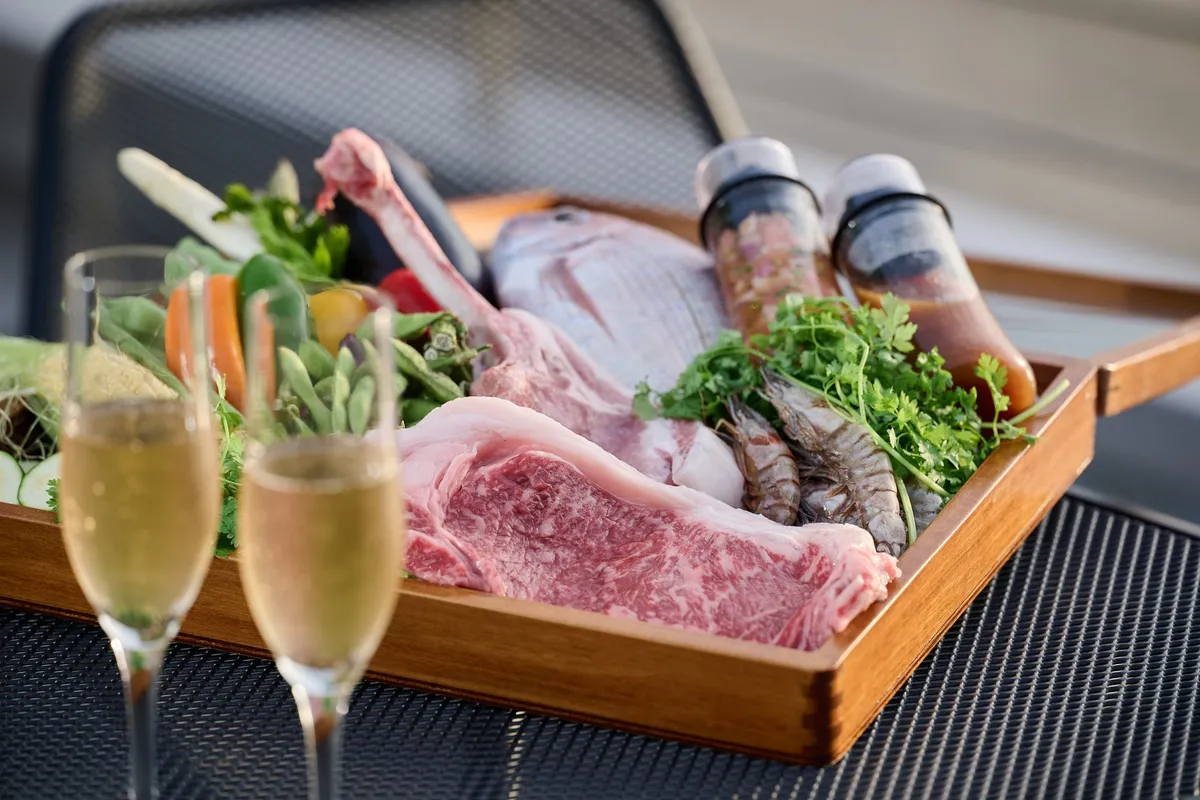 木箱に美しく盛られた肉や海鮮の食材とシャンパン