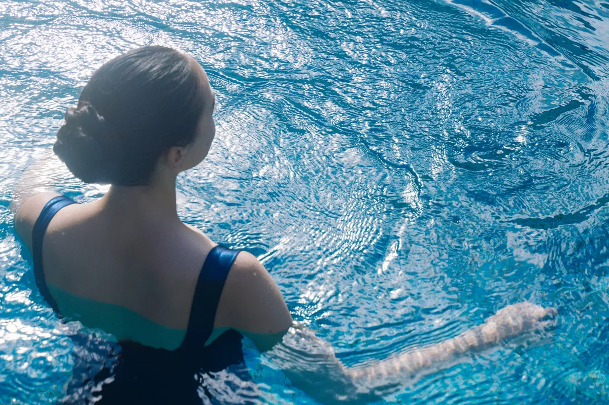 陽光に煌めく海水に身を浸す女性